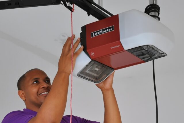 Technician performing a garage door opener repair, inspecting a LiftMaster unit to ensure smooth and reliable door operation. - Garage Opener Installation