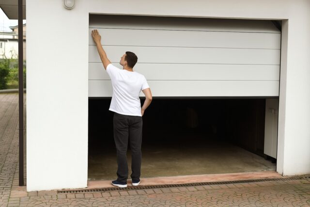 Garage door repair homeowner checking a stuck garage door panel.